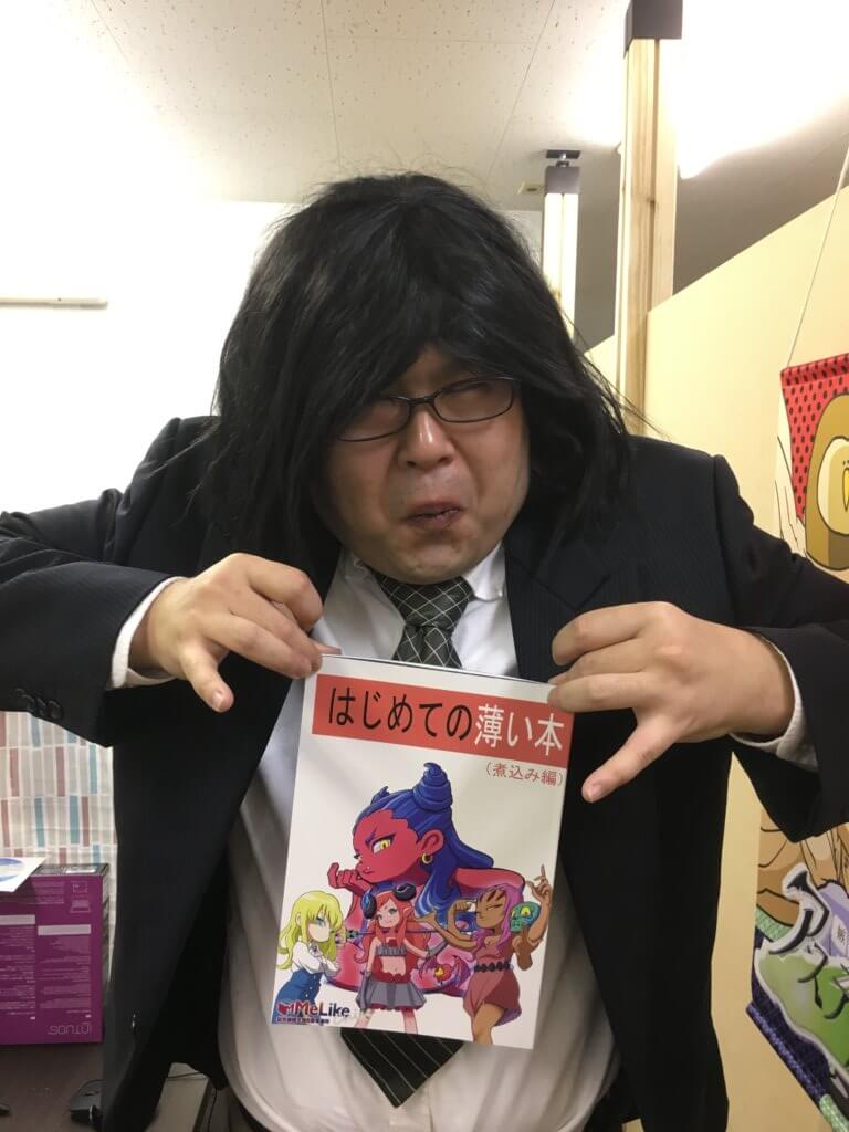 同人誌を広げて見せる男性