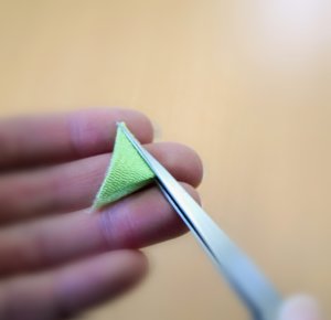 ピンセットで布を折りたたむ様子